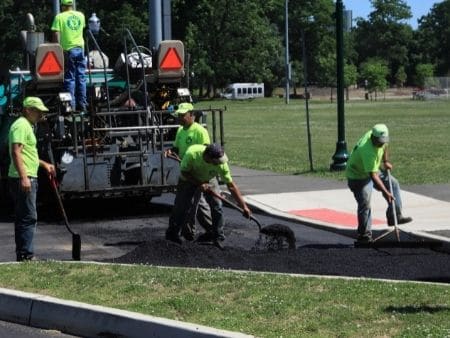 A group of asphalt contractors repaving a driveway.